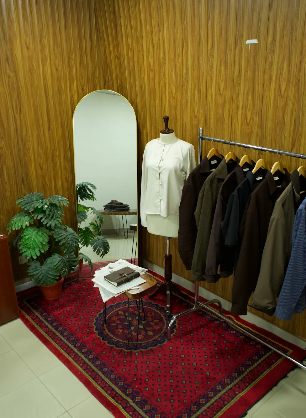 A white shirt on a mannequin beside a rack of jackets in the ASTA ARAY studio